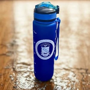 May include: A blue matte water bottle with a black and translucent blue flip-top lid and a carrying strap. The bottle features a white circular emblem with the text "Phi Eta Sigma Fraternity" and "1923" printed on the front, along with measurement markings.