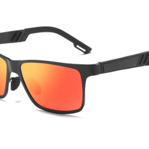 Puede incluir: Gafas de sol negras con montura rectangular y lentes de color naranja vibrante. Las patillas presentan un dise&ntilde;o texturizado y un sutil detalle de rayas. Estas gafas de sol ofrecen una est&eacute;tica moderna y deportiva.