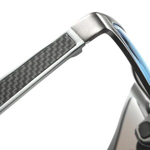 Puede incluir: Primer plano de gafas de sol modernas con montura de metal plateado y lentes azules. Las patillas presentan un patr&oacute;n de fibra de carbono para un look elegante. Dise&ntilde;o elegante y contempor&aacute;neo.