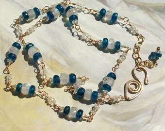 Peut inclure: Un collier en or avec des perles de pierres précieuses bleues et blanches. Le collier a un fermoir unique en forme de spirale.