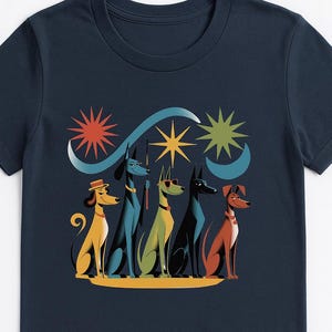 Könnte beinhalten: Marineblaues T-Shirt mit einer stilisierten Illustration von fünf Hunden in verschiedenen Farben und mit Accessoires. Die Hunde sind unter einem Design aus Sternen und einem Halbmond angeordnet. Die Grafik ist im Retro-Stil gehalten.