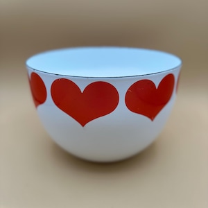 Puede incluir: Cuenco blanco con interior azul claro y borde negro. El exterior presenta un patrón repetido de grandes corazones rojos. El cuenco tiene un diseño simple pero encantador.