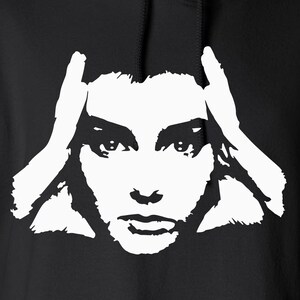 May include: Black hoodie with a white graphic of a woman's face, hands on her head. The sweatshirt has a drawstring hood and a kangaroo pocket. The brand name "Gildan Heavy Blend" is visible on the tag.
