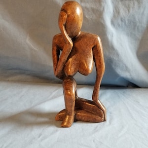 Hand carved wooden sculpture of a woman thinking