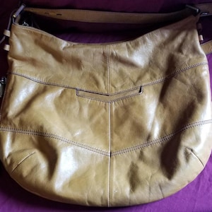 This is a tan leather hobo style shoulder bag made by HOBO