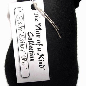 May include: A white tag with black text that reads "The 'Num of a Kind' Collection Sister Esther Gen."