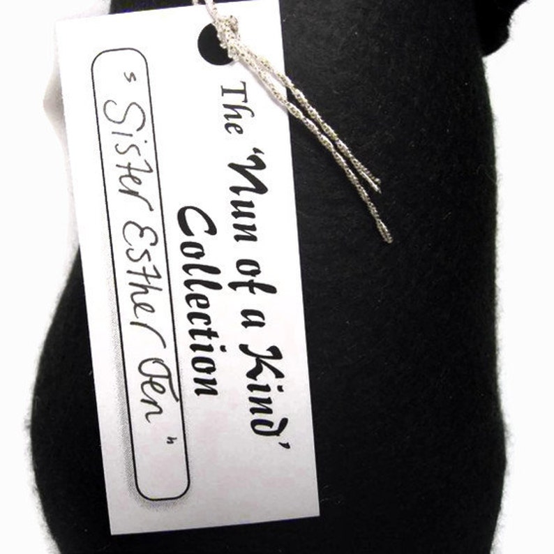May include: A white tag with black text that reads "The 'Num of a Kind' Collection Sister Esther Gen."