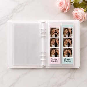 Puede incluir: Una carpeta blanca de seis anillas con fundas de pl&aacute;stico transparente que contiene dos tiras de fotos verticales. La tira izquierda tiene un fondo rosa claro y la derecha un fondo azul claro. Ambas tiras incluyen el texto Memory Station.