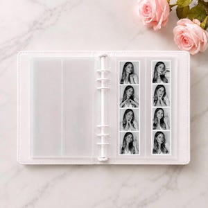 Puede incluir: Una carpeta blanca de seis anillas con fundas de pl&aacute;stico transparente que contiene dos tiras verticales de fotos en blanco y negro de fotomat&oacute;n. Cada tira muestra cuatro poses distintas de una persona. La carpeta est&aacute; abierta.