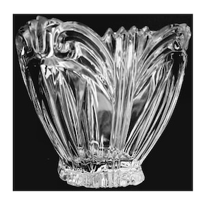 May include: A clear glass bowl with a decorative, intricate design. The bowl has a wide, shallow shape and a scalloped edge.