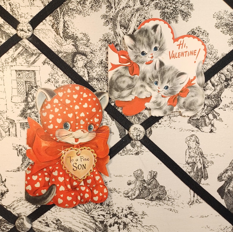 Op de afbeelding: Vintage Valentijnskaarten met kattenillustraties. E&eacute;n kaart toont een rode kat met hartpatronen en de tekst "To a Fine Son". Een andere kaart toont twee grijze kittens met rode strikken en de tekst "Hi, Valentine!"