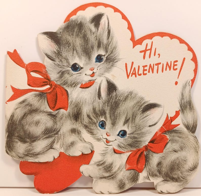 Op de afbeelding: Vintage Valentijnsdagkaart met twee grijze kittens met blauwe ogen en rode strikken. De kittens omarmen een rood hart. De kaart heeft de tekst "Hi, Valentine!" in het rood.