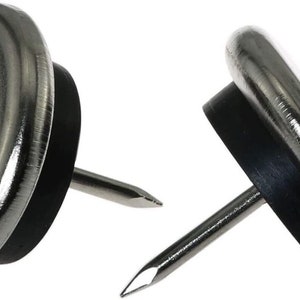 Puede incluir: Dos deslizadores de muebles plateados con almohadillas de goma negra y tallos de clavos.