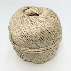 May include: A ball of natural-colored twine, tightly wound into a spherical shape. The twine appears to be made of a fibrous material, with visible strands and a slightly textured surface. A single strand wraps around the ball's circumference.
