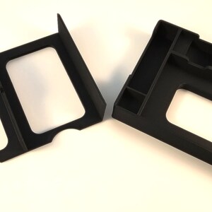 May include: Two black plastic organizers for board games. One organizer has two compartments and the other has multiple compartments.