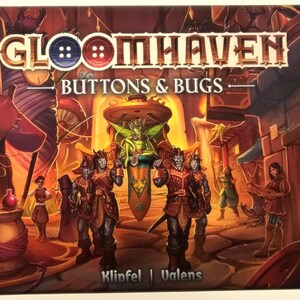 May include: A board game box cover featuring a fantasy scene with a green fairy-like creature on a throne, surrounded by four characters with red and brown clothing. The box cover is titled "Gloomhaven: Buttons & Bugs" and features the Cephalofair Games logo.
