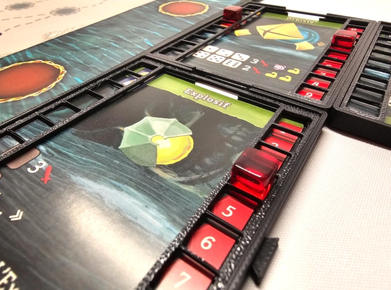 Puede incluir: Un tablero de juego negro con dados rojos y blancos y una carta que dice "Explosif".