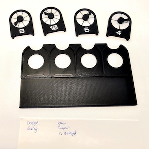 May include: Black plastic game pieces with numbers 4, 6, 8, and 10. The pieces are on a black plastic stand with four slots. The stand has a blank space below the slots. A handwritten note says "Dodge Gang" and "When Raven is delayed".