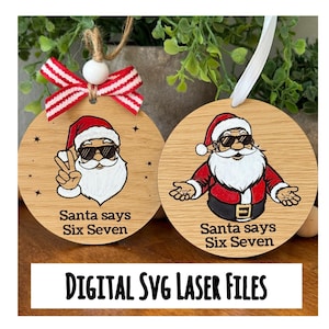 May include: Two wooden Christmas ornaments featuring Santa Claus. One shows Santa giving a peace sign, the other with open arms. Both Santas wear sunglasses and have the text "Santa says Six Seven". A red and white striped bow and white ribbon are attached.