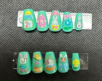 Puede incluir: Conjunto de diez uñas postizas de presión de temática de Pascua, de color verde y blanco. Las uñas presentan varios diseños, incluyendo conejos, huevos, flores y lazos.