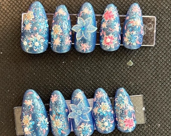 May include: Set of ten blue and white floral press-on nails with glitter and rhinestones.