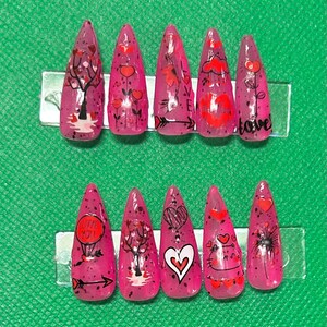 Puede incluir: Conjunto de diez uñas postizas rosas con diseños temáticos de San Valentín. Los diseños incluyen corazones, flechas, árboles y las palabras "love you" y "love".