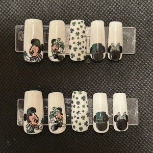May include: Set of ten false fingernails with a green shamrock and Mickey Mouse and Minnie Mouse designs.