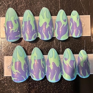 May include: Set of ten false nails with a green and purple flame design.