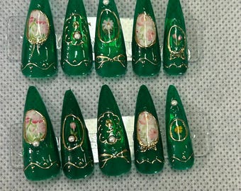 May include: Set of ten green and gold false nails with floral designs. Each nail has a different floral design with a pearl accent.
