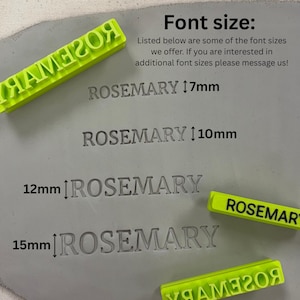 May include: Bright neon green plastic stamps with the word ROSEMARY in reverse, used to imprint the name into a grey clay surface. The image displays four examples of the name ROSEMARY pressed into the clay at 7mm, 10mm, 12mm, and 15mm heights.
