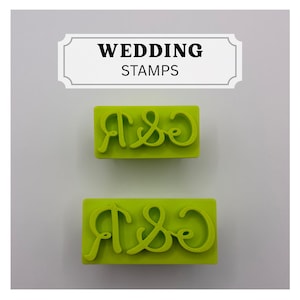 May include: Two lime green rectangular stamps featuring the raised script letters A & C. Above the stamps, a white rectangular label with a decorative border displays the black text WEDDING STAMPS in a bold, serif font on a white background.