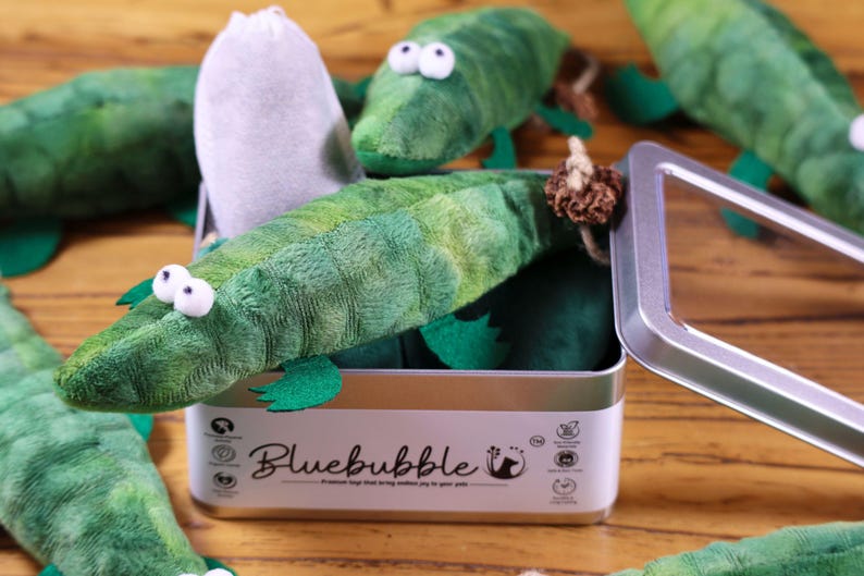 Peut inclure: Un ensemble de jouets en peluche en forme d'alligator vert dans une bo&icirc;te en m&eacute;tal avec le nom de la marque "Bluebubble" imprim&eacute; sur la bo&icirc;te. Les jouets sont con&ccedil;us pour &ecirc;tre des jouets pour chats.