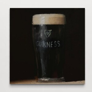 Pu&ograve; includere: Un primo piano di un bicchiere di birra Guinness. Il bicchiere &egrave; pieno di stout scuro e ha una schiuma bianca. Il logo Guinness &egrave; visibile sul lato del bicchiere.