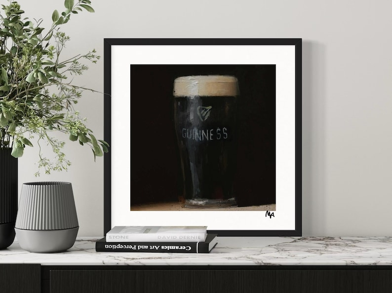 Pu&ograve; includere: Un dipinto in bianco e nero di un bicchiere di birra Guinness. Il bicchiere &egrave; su uno sfondo scuro e il logo Guinness &egrave; visibile sul lato del bicchiere.