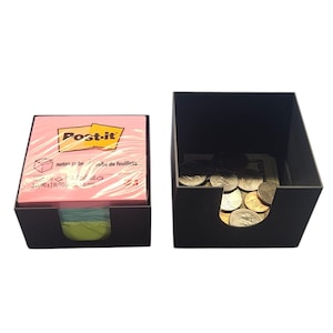 Op de afbeelding: Twee zwarte bureau-organizers. Eén bevat een roze Post-it-kubus, de andere munten. De Post-it-kubus is voorzien van het Post-it-merklogo en productinformatie.