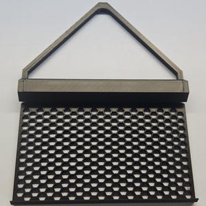 May include: A dark gray, 3D-printed object with a honeycomb pattern and a triangular handle. The object has a rectangular base and a series of hexagonal openings. The handle is a triangle shape.
