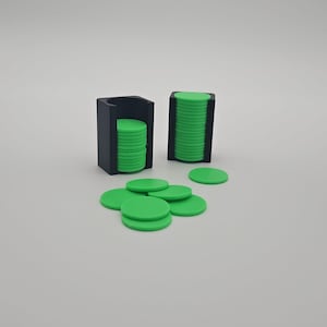 Può includere: Un set di fiches da poker verdi con due porta fiches neri. Alcune fiches sono impilate nei porta fiches, mentre altre sono sparse. Le fiches sono circolari e hanno una superficie liscia.
