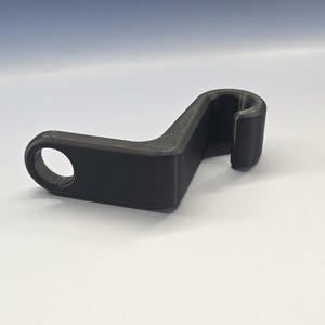 May include: A black plastic hook with a rounded end and a curved shape. The hook is designed to hang items on a wall or other surface.