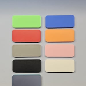 May include: A collection of ten rectangular objects in various colors, including green, blue, red, orange, gray, pink, black, and cream. The objects are arranged in two rows of five on a light gray surface.