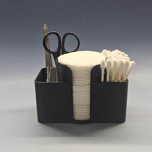 May include: A black plastic organizer with three compartments. The compartments hold cotton rounds, cotton swabs, and a pair of scissors and a nail file.