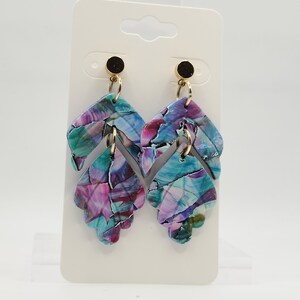 May include: A pair of dangle earrings with a multi-colored abstract pattern. The earrings are made of polymer clay and have a gold-tone hook.