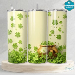 May include: Three stainless steel tumblers with a design of green four-leaf clovers and a gold pot of gold. The tumblers are on a light wood surface. 9 free designs included!