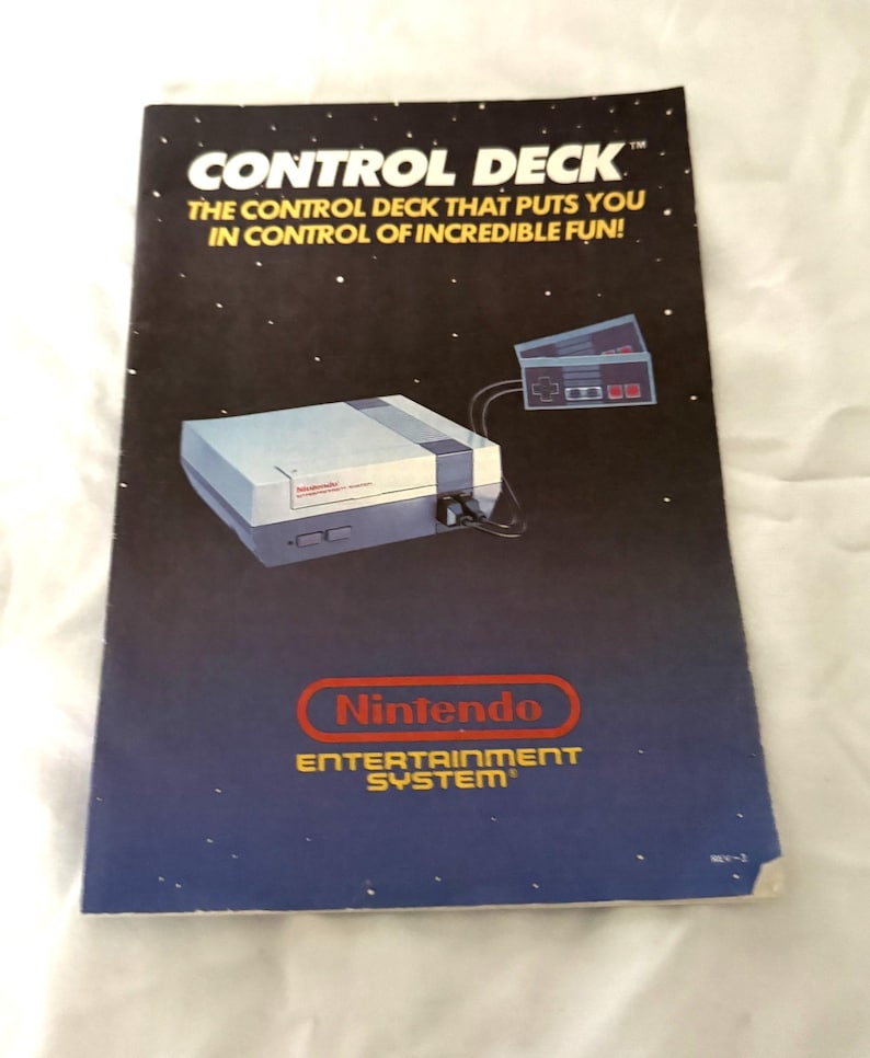 May include: A vintage Nintendo Entertainment System advertisement. The cover features the text "CONTROL DECK" and "THE CONTROL DECK THAT PUTS YOU IN CONTROL OF INCREDIBLE FUN!" with an illustration of the console and controller. The Nintendo logo is also visible.