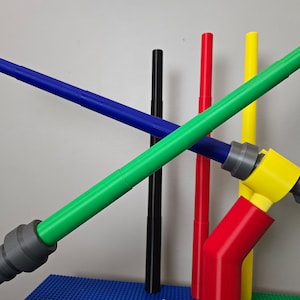 May include: Five colorful plastic tubes, some connected with gray connectors, forming a structure. The tubes are green, blue, red, yellow, and black.
