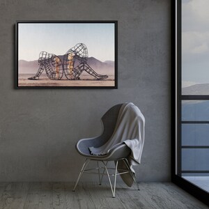 May include: A framed photograph of a metal sculpture of two figures, one larger than the other, sitting on a desert landscape. The sculpture is made of wire and appears to be a representation of a mother and child.