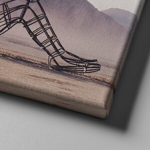 May include: A close-up of a wire sculpture of a person's leg and foot. The sculpture is made of thin wire and is painted in a metallic silver color. The sculpture is set against a blurred background of a mountain range.