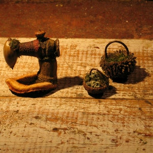 Peut inclure: Une machine à coudre miniature en bois faite d' glands et d'autres matériaux naturels, avec deux petits paniers en glands remplis de mousse et de feuilles.