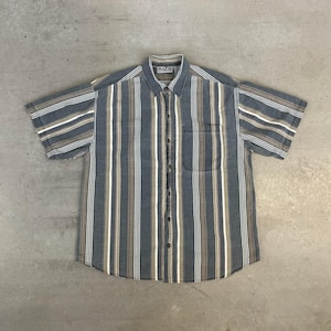 May include: A short-sleeve button-down shirt featuring a vertical striped pattern in shades of slate blue, tan, and white. The shirt includes a standard collar, a single chest pocket on the left side, and a front button placket with a Blazer brand label.