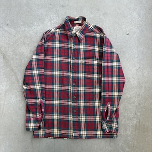 May include: A long-sleeved, button-down flannel shirt in a classic plaid pattern. The shirt features a colour scheme of red, navy blue, and cream, with a button-down collar and a single chest pocket. The shirt is laid flat on a grey surface.