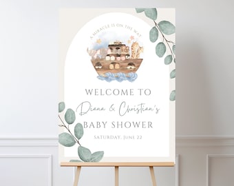 May include: A welcome sign for a baby shower with a light brown background and a blue and white illustration of a boat with animals on it. The text on the sign reads "A miracle is on the way" and "Welcome to Diana & Christian's Baby Shower, Saturday, June 22".